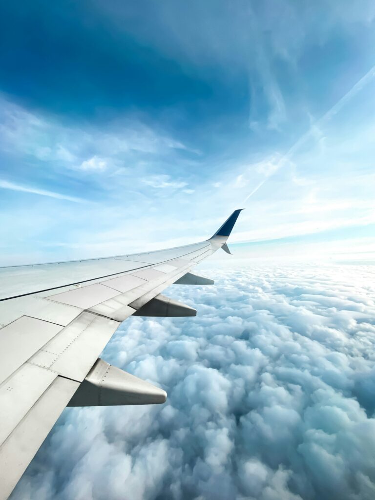 Photo of an airplane wing hovering over clouds in the sky.