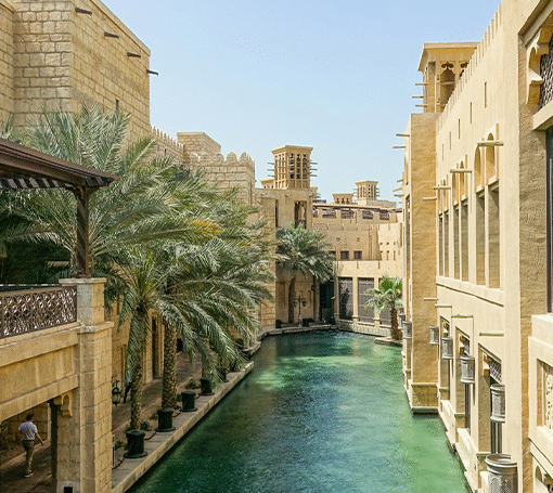 Photo of a sparkling blue creek in the middle of tall sand-colored middle-east inspired buildings.