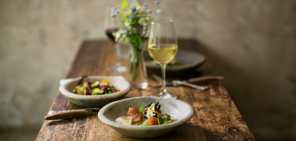 Photo os a rustic table showcasing locally grown food and wine.