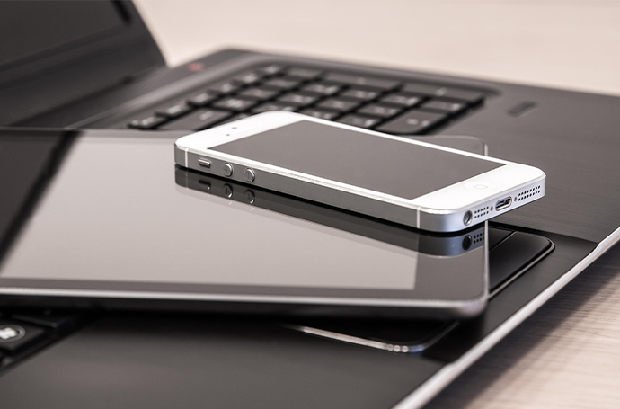 A cell phone and laptop stacked together, highlighting a modern digital workspace.