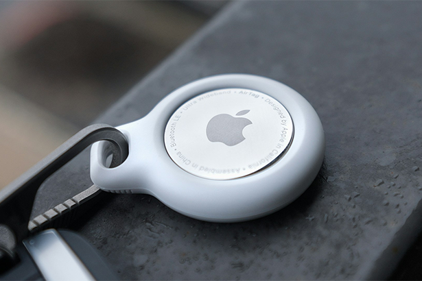 An Apple AirTag wrapped in a white Belkin keychain with a prominent white logo, showcasing the brand's signature style and design.