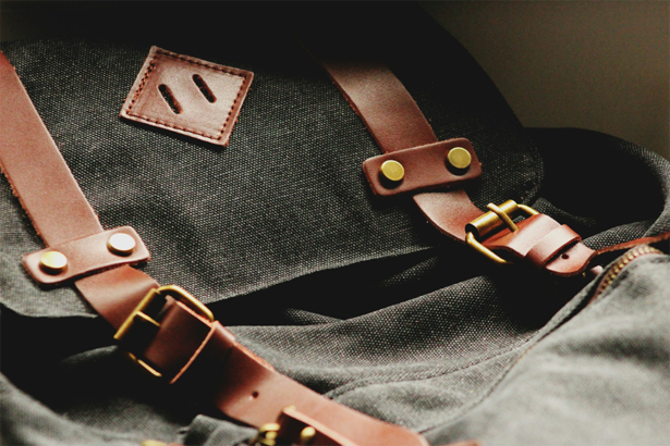 A black backpack featuring brown straps and a gold buckle, showcasing a stylish and functional design for everyday use on an airplane.
