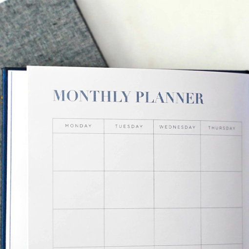 Photo of an open monthly planner notebook in front of a closed bullet journal.