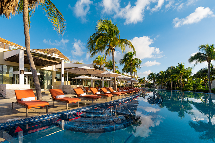 Infinity pool with orange lounge chairs and palm trees at Moon Palace The Grand Cancun — all-inclusive resort vacation packages planned by My Tailored Escape, luxury travel advisor serving Washington DC, Maryland, Virginia and nationwide